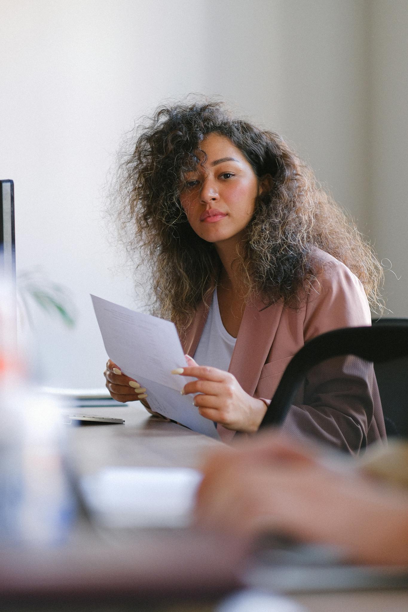 Confident businesswoman reviewing documents in modern office setting, focused and professional.