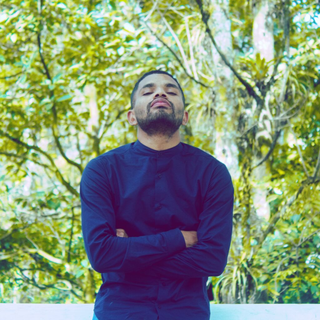 man-standing-with-arms-crossed-against-trees